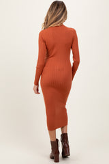 woman wearing an orange ribbed maternity dress with long sleeves and a fitted silhouette, showing off her baby bump from the back