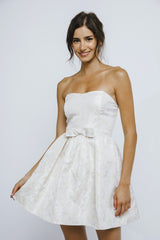 woman wearing a strapless white floral party dress with a bow at the waist
