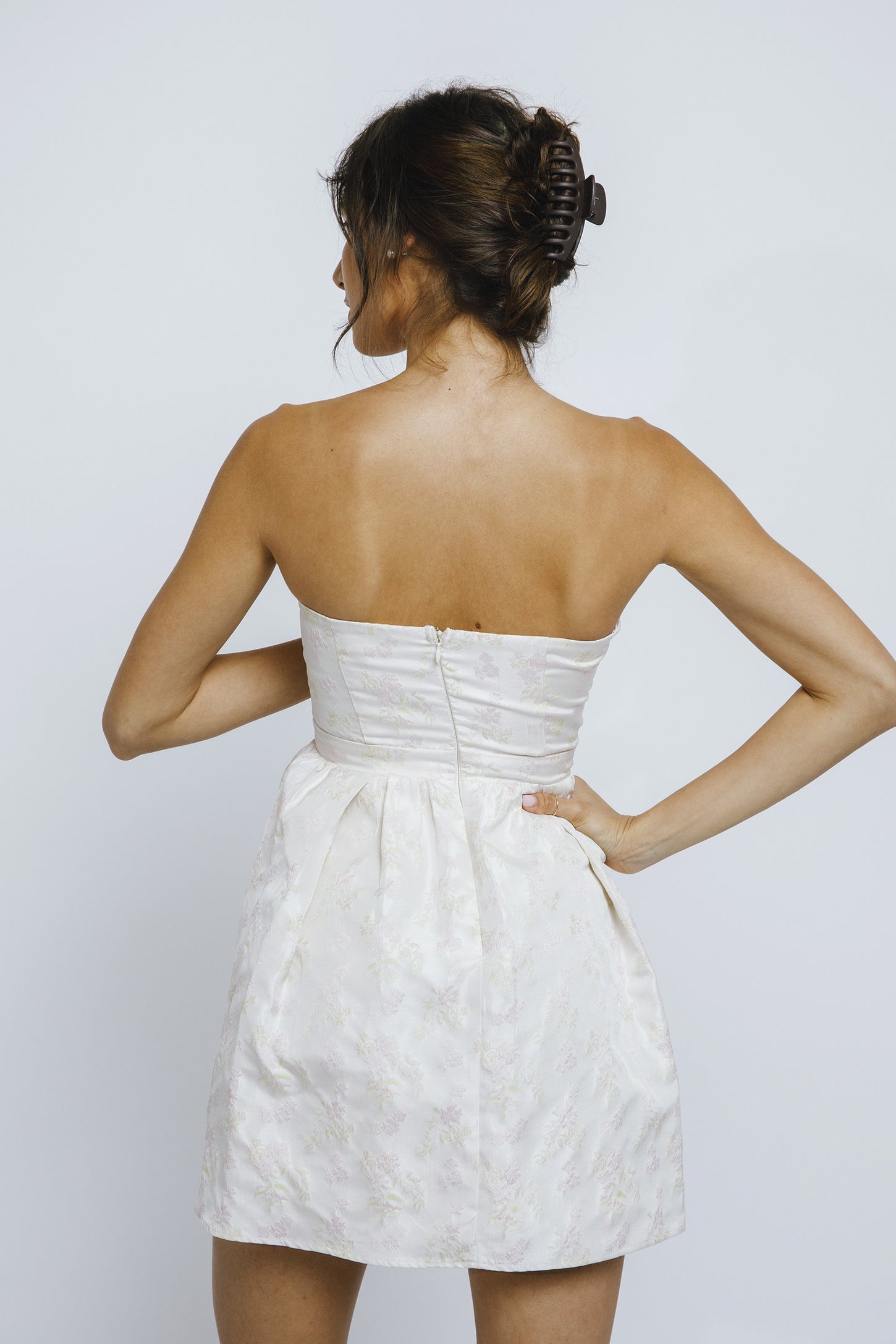 woman wearing a strapless white floral dress with a fitted bodice and a flared skirt, shown from the back