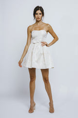 woman wearing a strapless ivory dress with a fitted bodice and flared skirt, posing with one hand on her hip