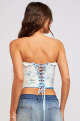 woman wearing a floral print strapless corset top with lace-up details, paired with denim shorts