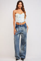 woman wearing a fitted corset top with print and high-waisted wide-leg jeans