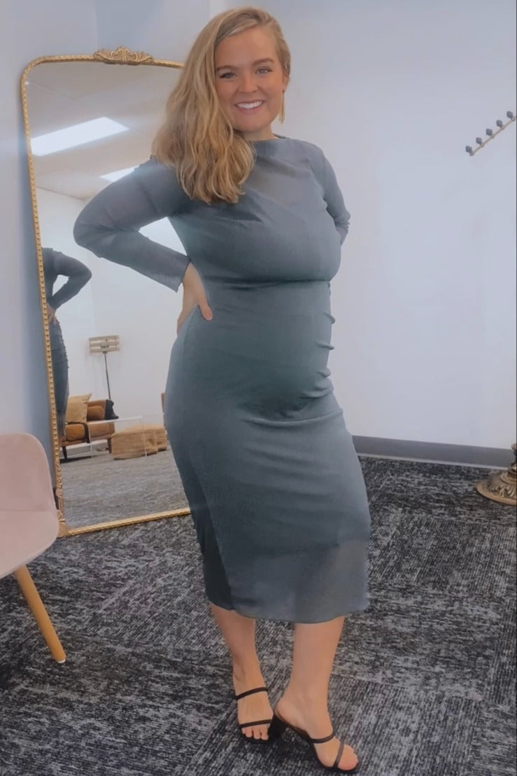 woman wearing a grey long sleeve maternity dress highlighting her baby bump