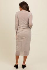 woman wearing a light beige long sleeve maternity dress with a form-fitting silhouette and mid-length hem