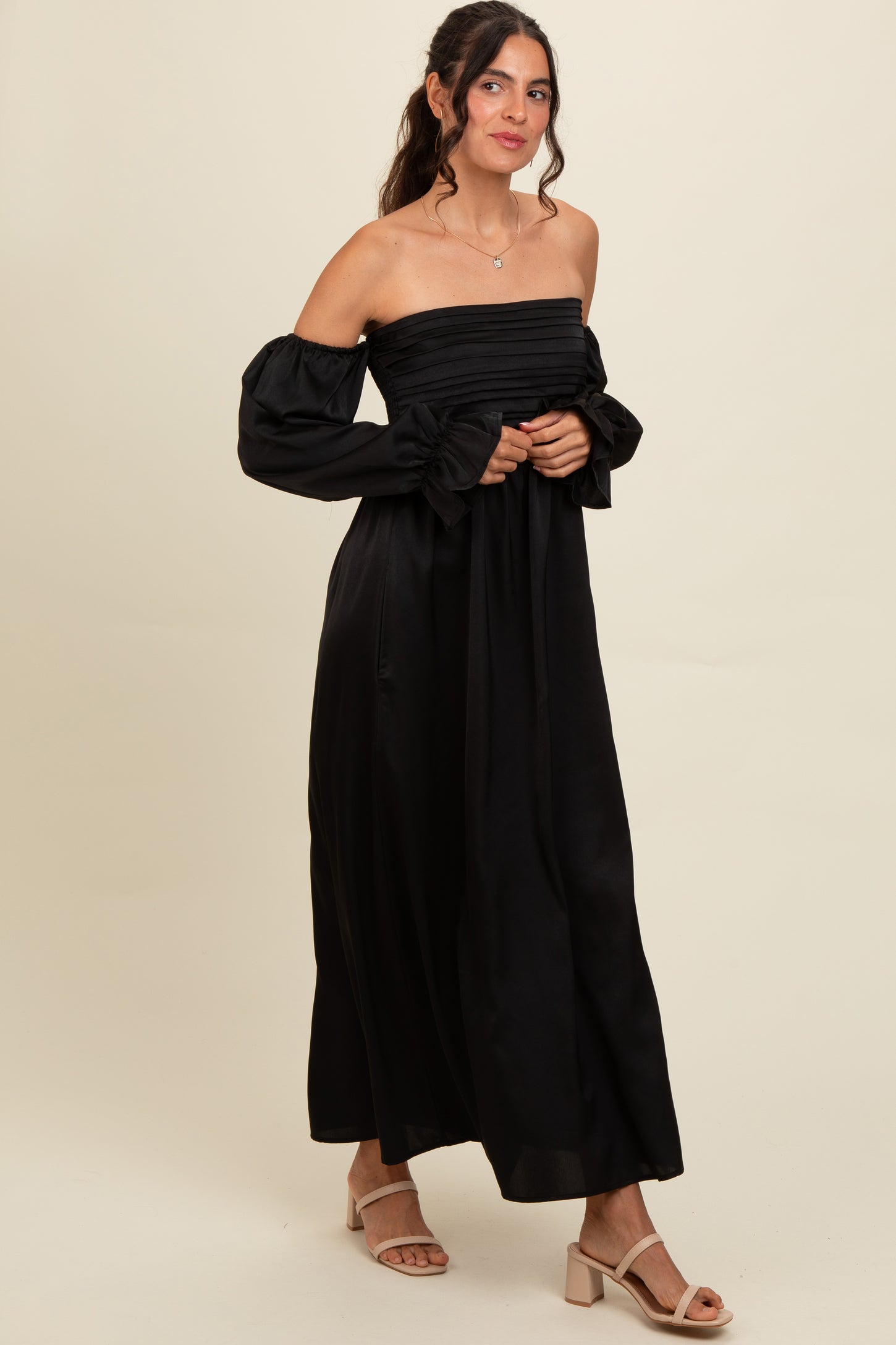 woman wearing a black off-the-shoulder maxi dress with puff sleeves and a fitted bodice