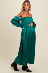 woman wearing a green off-the-shoulder maternity dress with ruffled sleeves and a visible baby bump