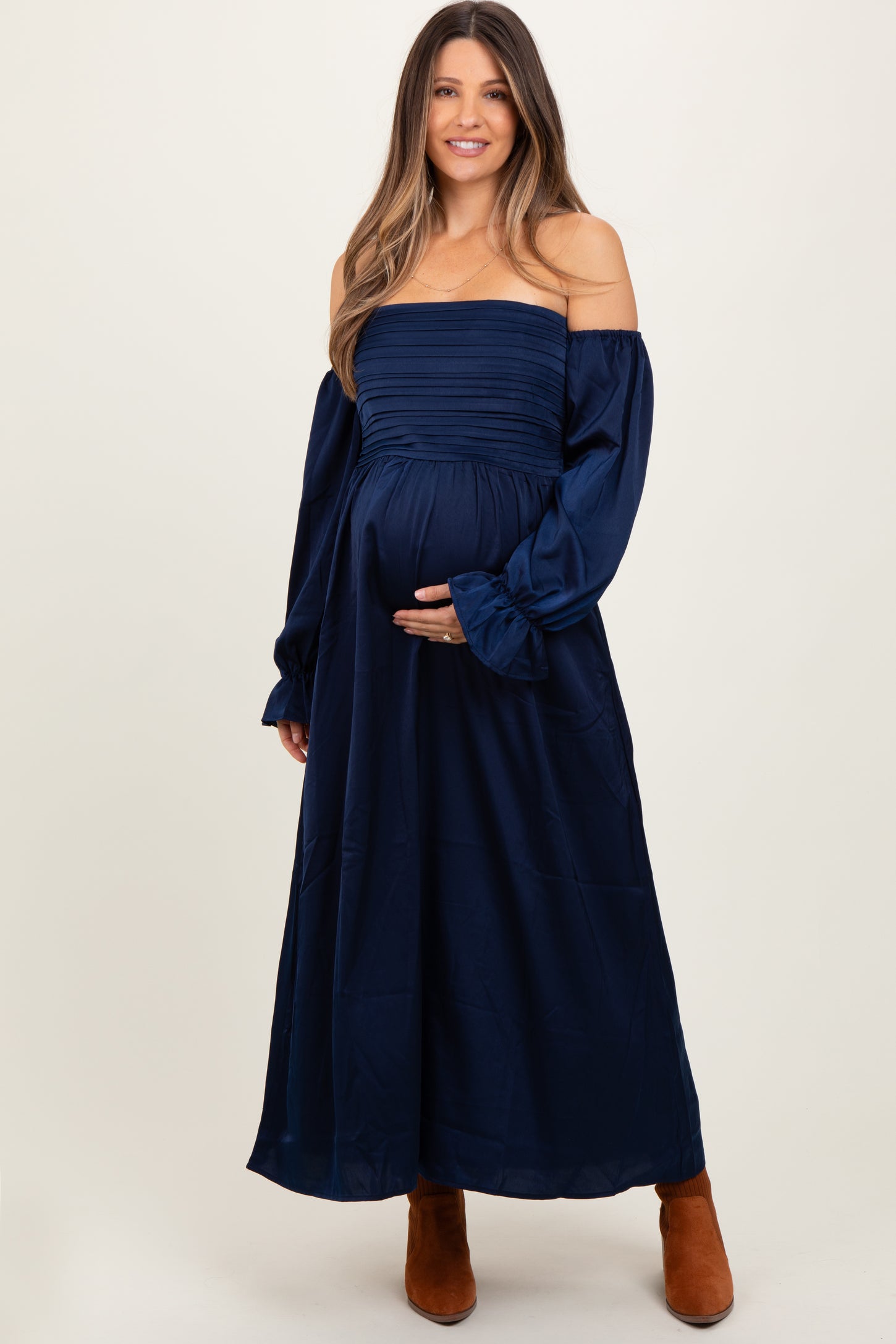 woman wearing a navy off-the-shoulder maternity dress and holding her baby bump