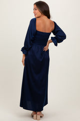 woman wearing a navy blue maternity maxi dress with smocked bodice and long puff sleeves, showing a baby bump from behind