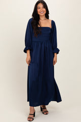 woman wearing a navy blue long sleeve maxi dress with a fitted bodice and puffed sleeves