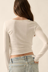 woman wearing a fitted white long sleeve top with a scoop back and light blue high-waisted jeans