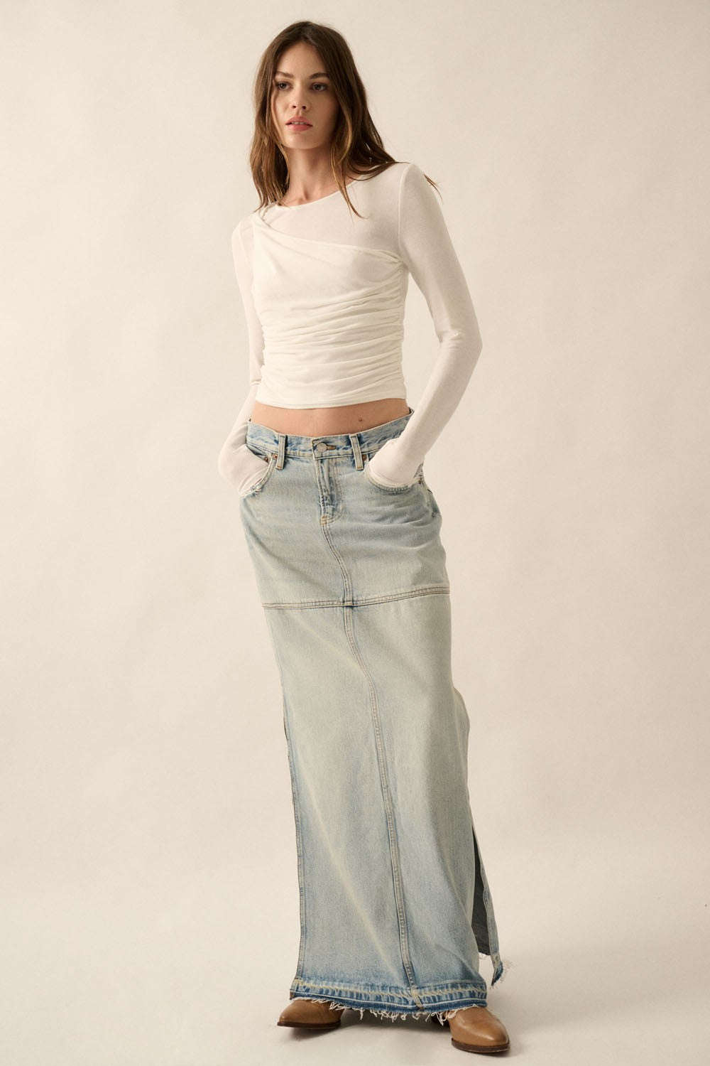woman wearing a white long sleeve crop top and a light wash denim maxi skirt