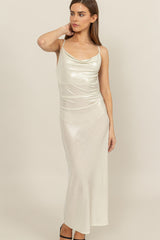 woman wearing a shimmery silver spaghetti strap maxi dress with a draped neckline and fitted silhouette