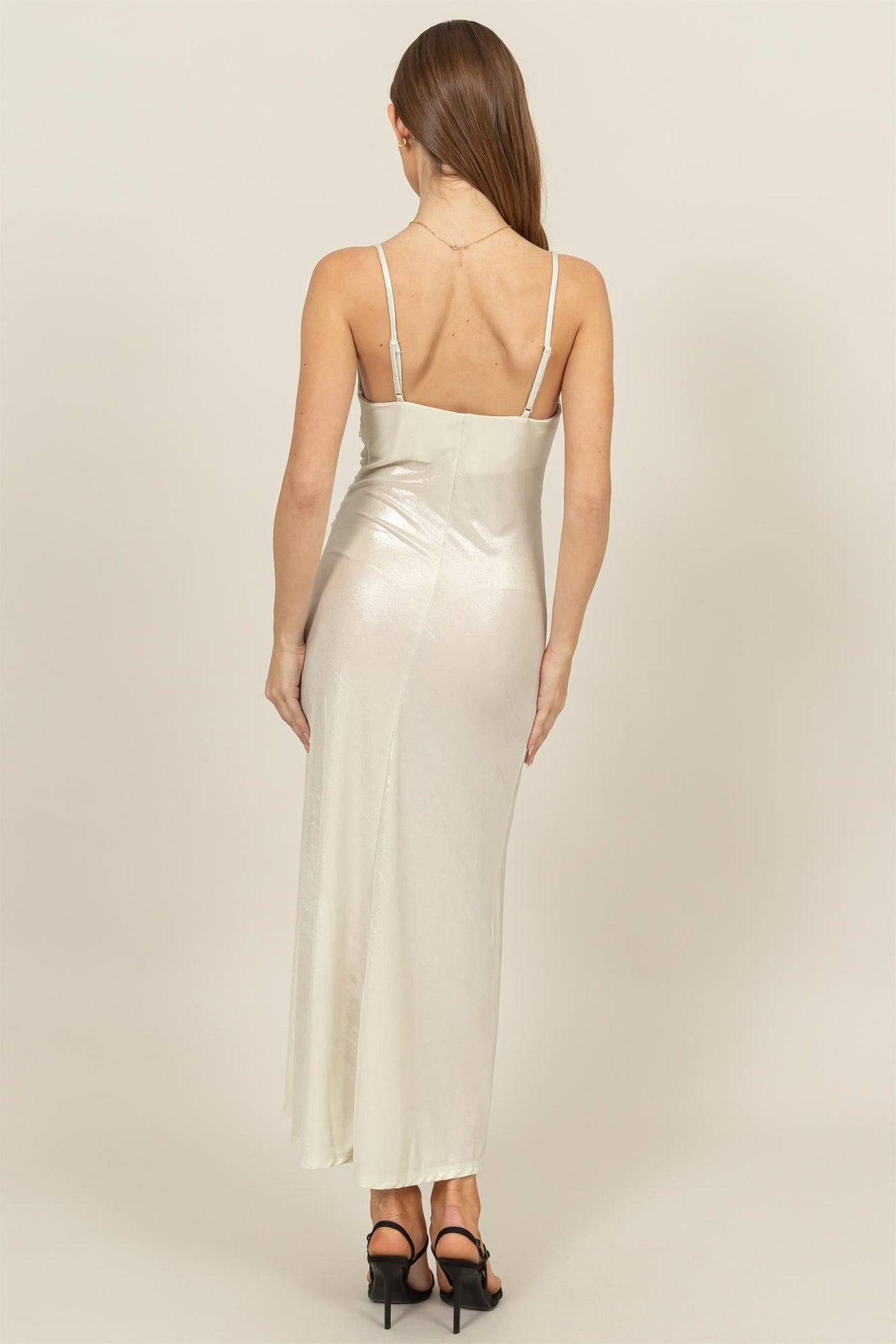 woman wearing a silver satin maxi dress with thin straps, viewed from the back
