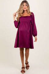 woman wearing a purple short sleeve maternity dress with a smocked bodice and puff sleeves, showcasing her baby bump