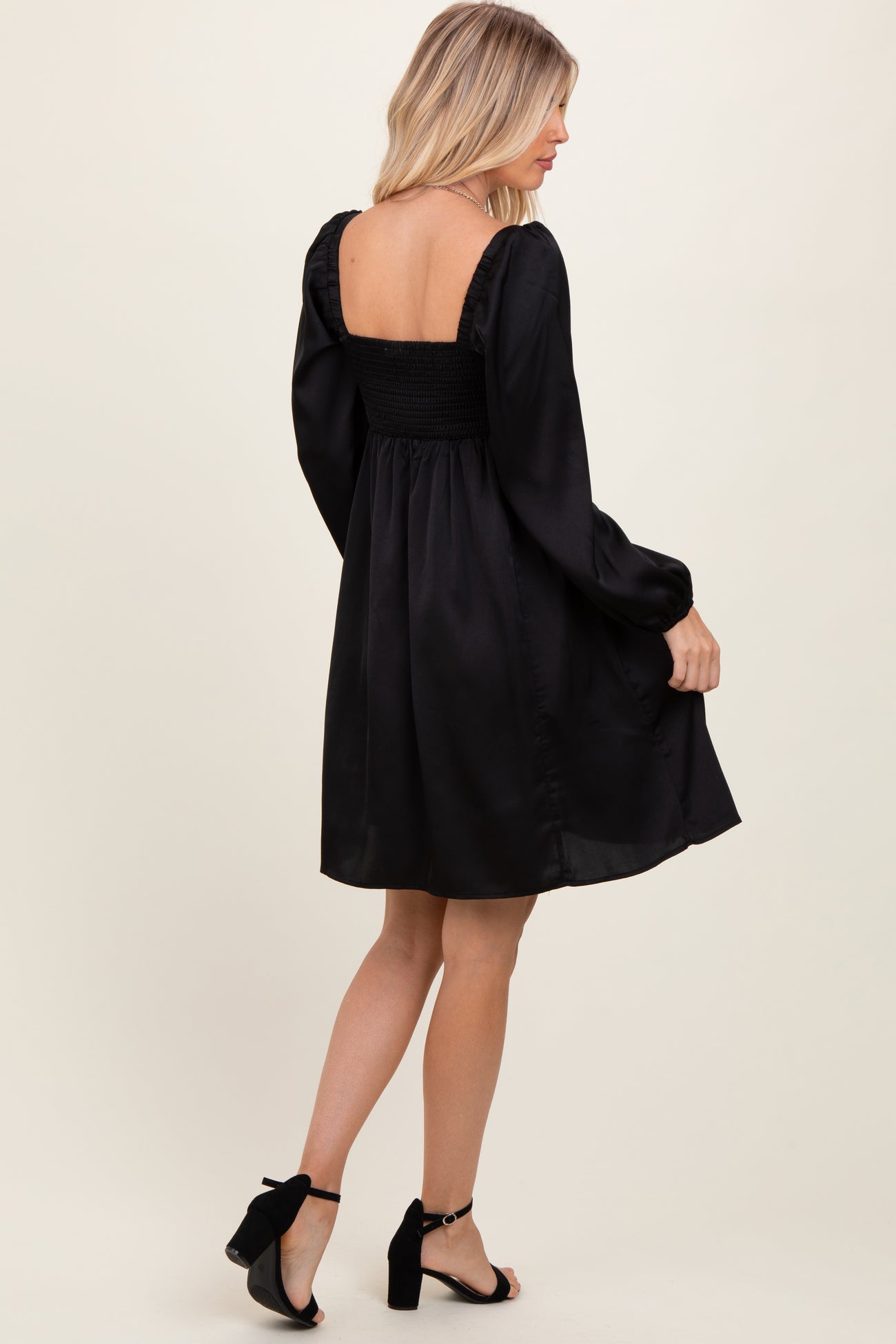 woman wearing a black smocked back long sleeve dress with a flared skirt and open back