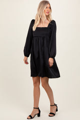 woman wearing a black short dress with puff sleeves and a square neckline, styled with black heels