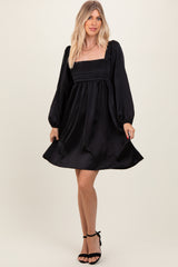 woman wearing a black satin puff sleeve mini dress with a square neckline and a fitted bodice