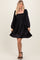 woman wearing a black satin puff sleeve mini dress with a square neckline and a fitted bodice
