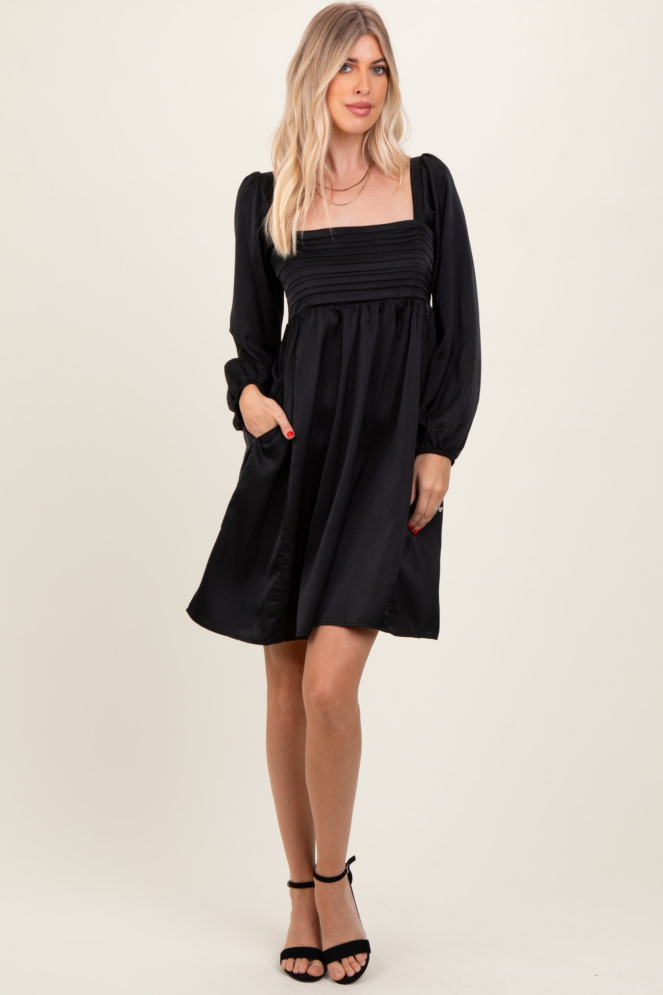 woman wearing a black puff sleeve mini dress with a square neckline and side pockets