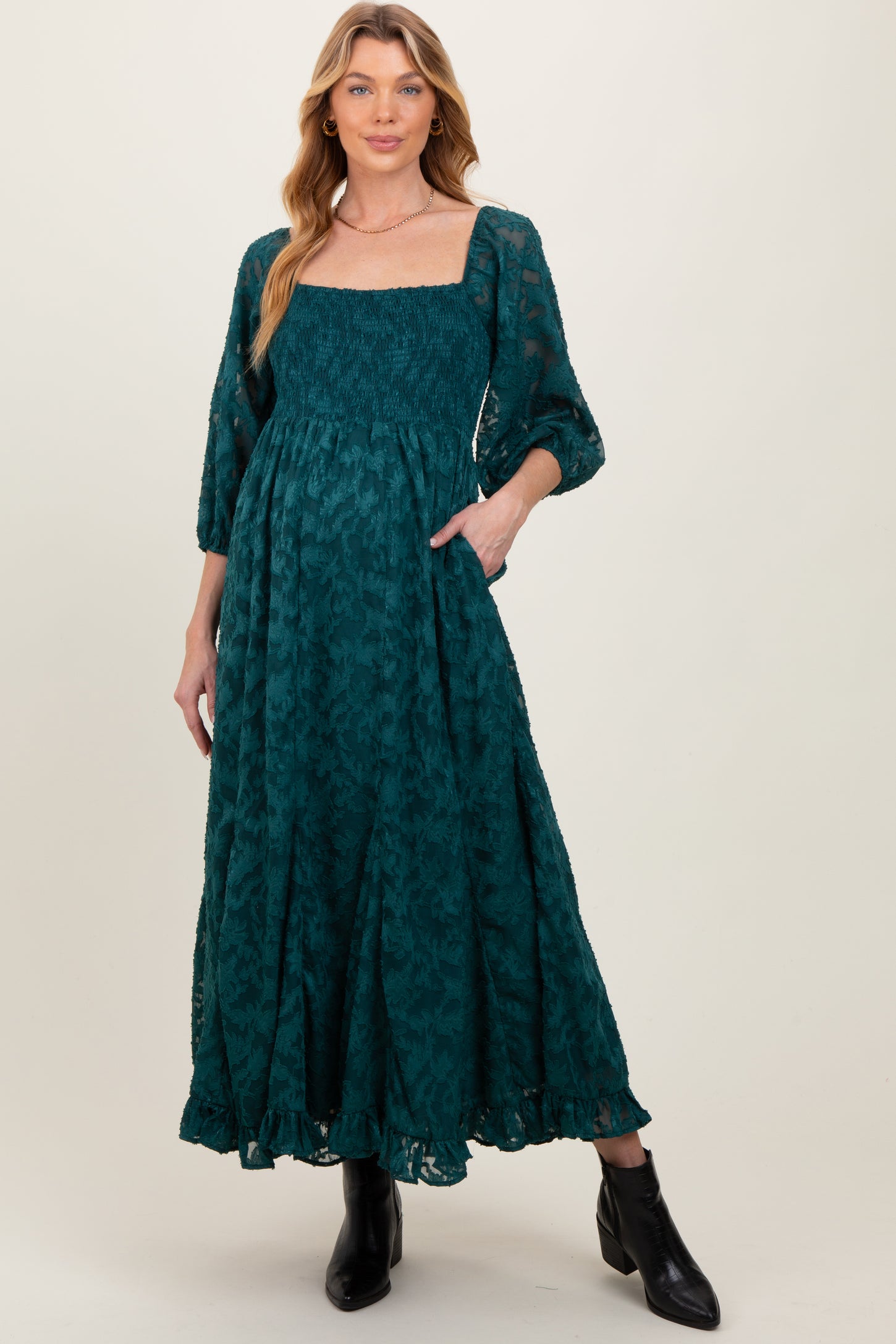 woman wearing a teal maternity dress with a square neckline, puff sleeves, and a relaxed fit, featuring a smocked bodice and pockets