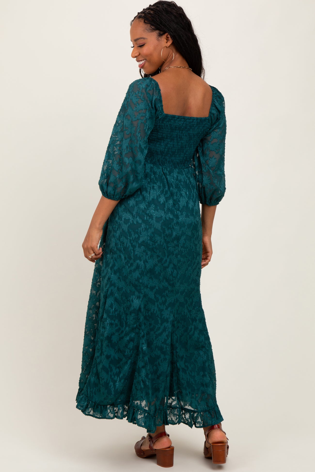 woman wearing a teal floral print maxi dress with puffed sleeves and a smocked bodice, shown from the back