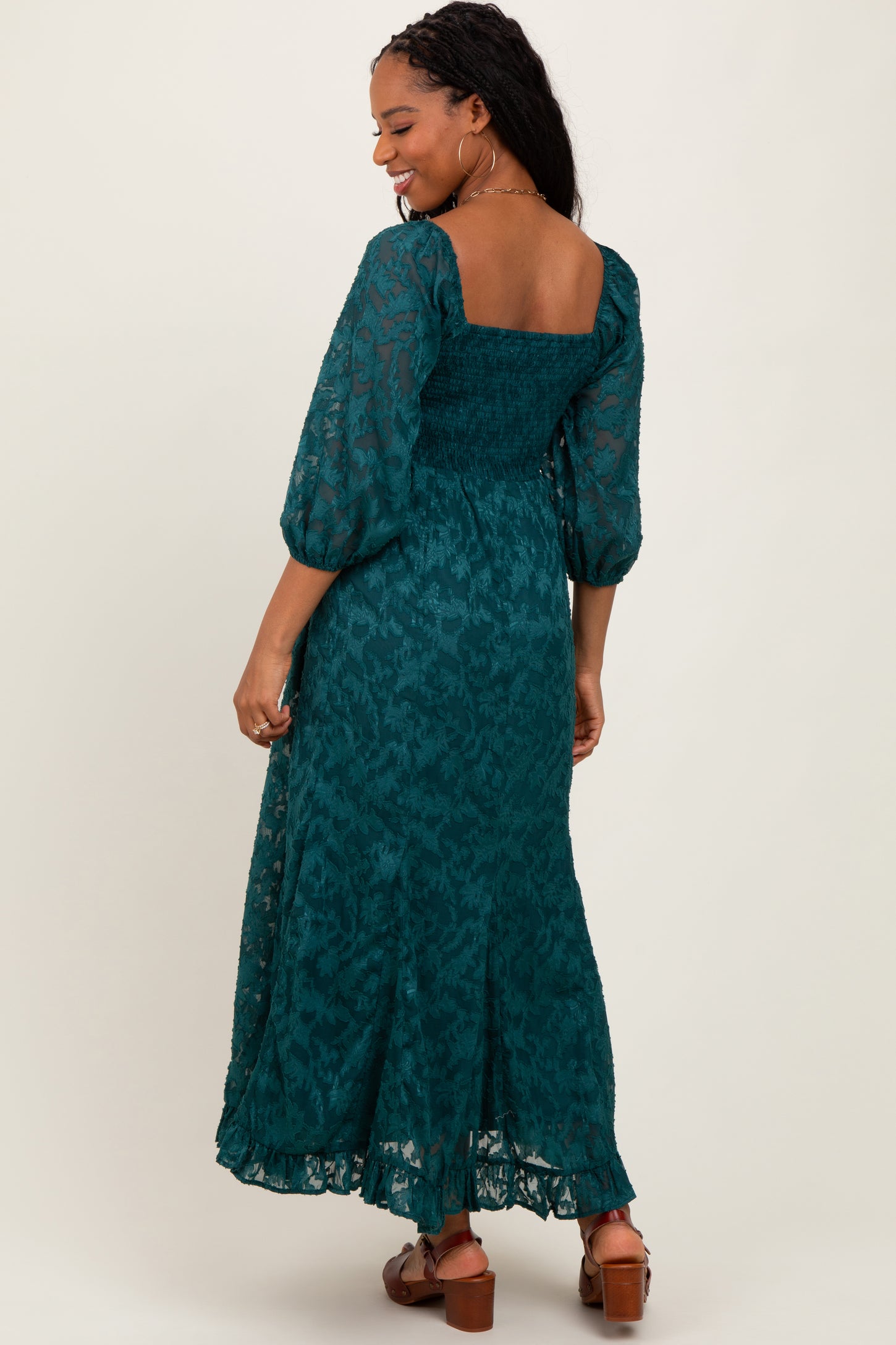 woman wearing a teal floral print maxi dress with puffed sleeves and a smocked bodice, shown from the back
