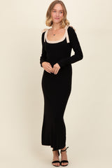 woman wearing a black long sleeve maxi dress with a beige scoop neckline and bow details on the shoulders