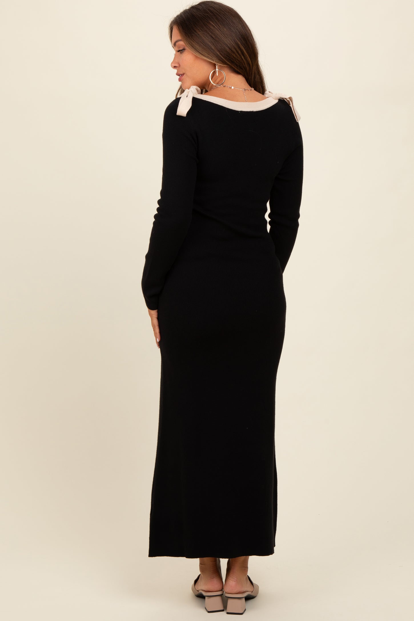 woman wearing a black maternity maxi dress with pink shoulder ties, showcasing her baby bump from the back