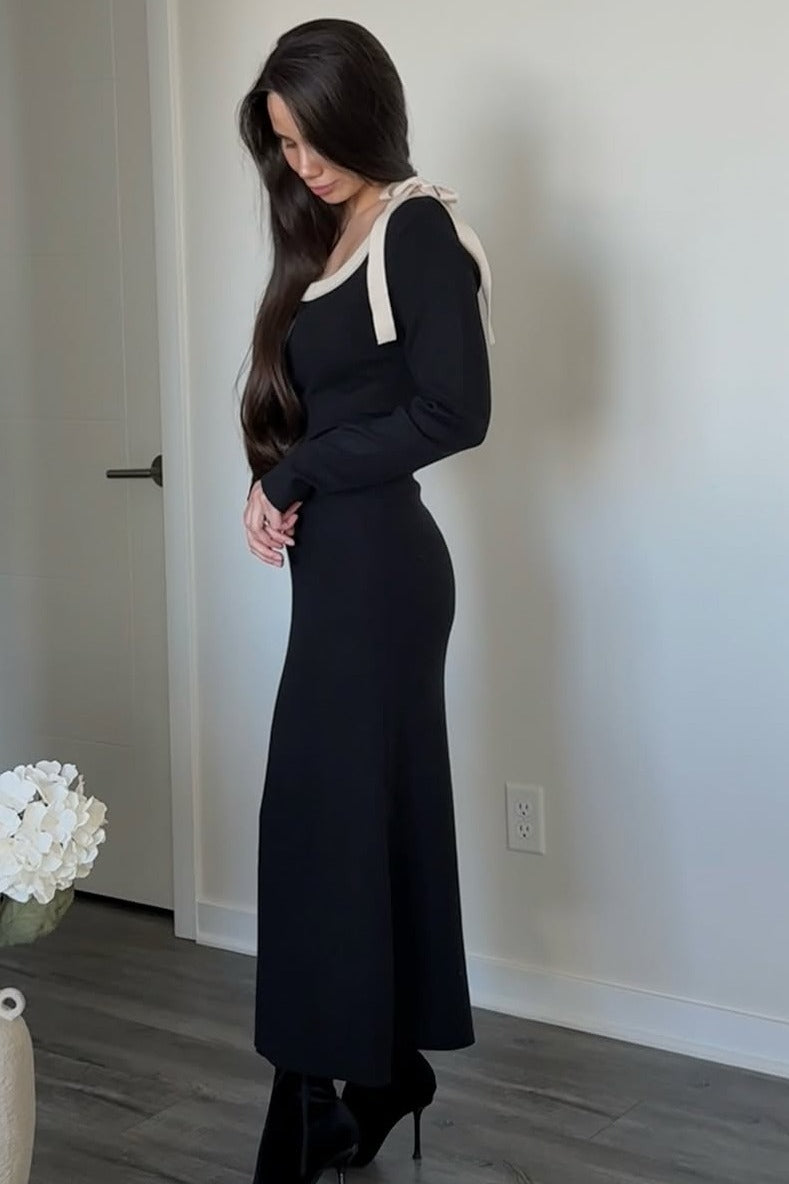 woman wearing a black long sleeve dress with a cream-colored shoulder strap detail and high heels