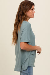 woman wearing a loose-fitting teal short sleeve top with a relaxed silhouette