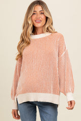 woman wearing a cream and orange striped maternity sweater with oversized sleeves and relaxed fit