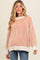 woman wearing a cream and orange striped maternity sweater with oversized sleeves and relaxed fit