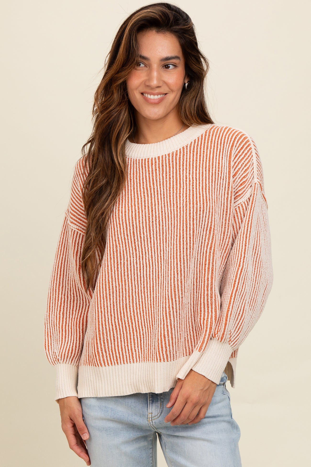 woman wearing a striped orange and cream oversized sweater with balloon sleeves and casual jeans