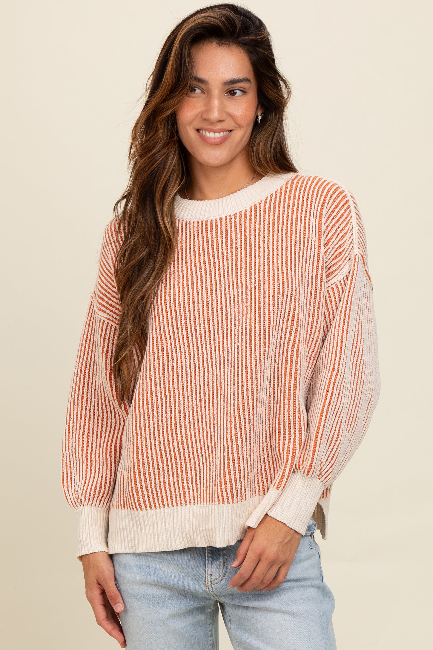 woman wearing a striped orange and cream oversized sweater with balloon sleeves and casual jeans