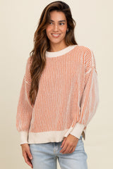 woman wearing a striped orange and cream oversized sweater with balloon sleeves and casual jeans