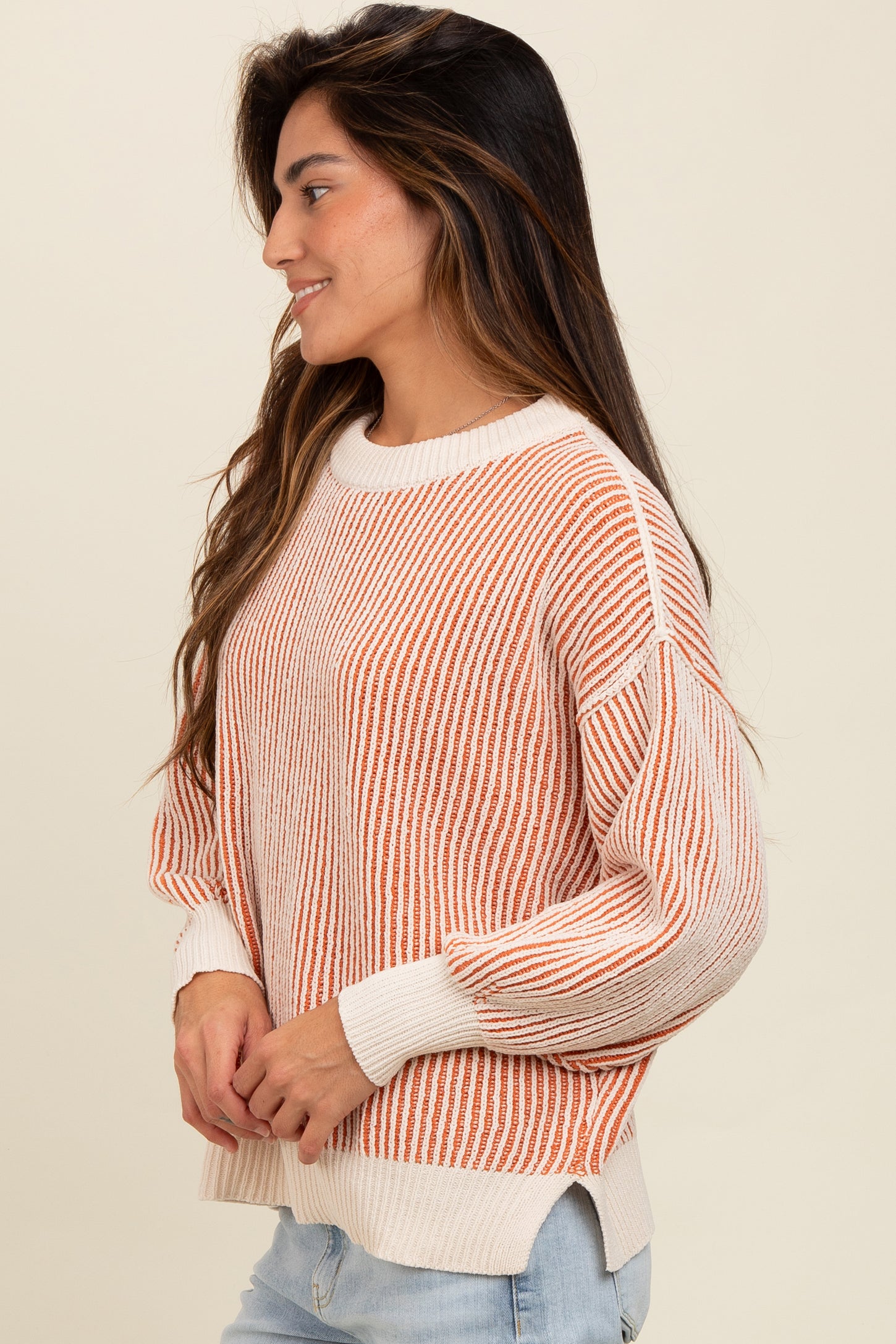 woman wearing an orange and white striped knit sweater with a relaxed fit and long sleeves
