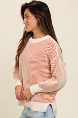 woman wearing an orange and white striped knit sweater with a relaxed fit and long sleeves