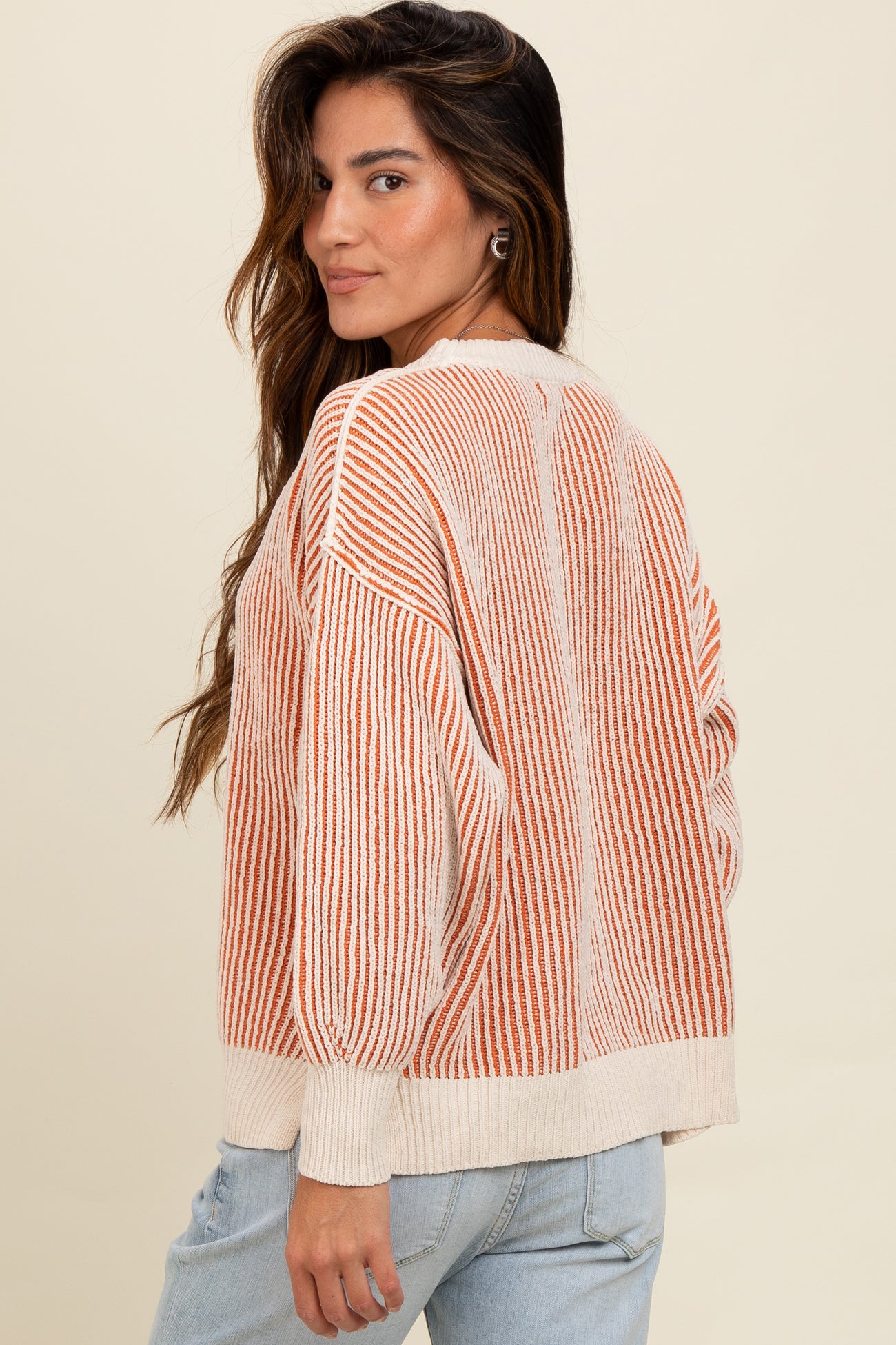 woman wearing a cream and orange striped oversized sweater with balloon sleeves and a round neckline