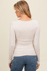 woman wearing a light beige long sleeve maternity top with ruching detail, showing the back view