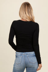 woman wearing a black long sleeve top with ruching details, shown from the back with light wash jeans