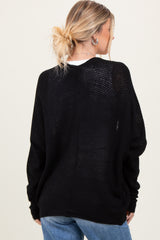 woman wearing a loose-fitting black knit sweater paired with light blue jeans, viewed from the back