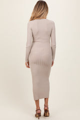 woman wearing a ribbed beige maternity dress with long sleeves and a midi length, showing a subtle baby bump