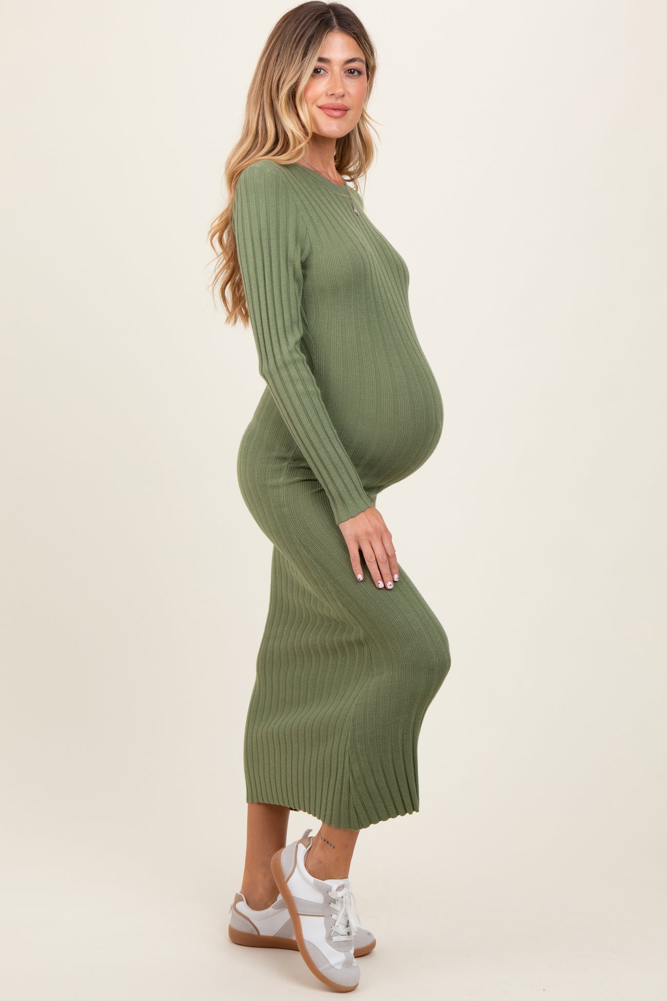 woman wearing a dark green ribbed maternity dress and showing her baby bump