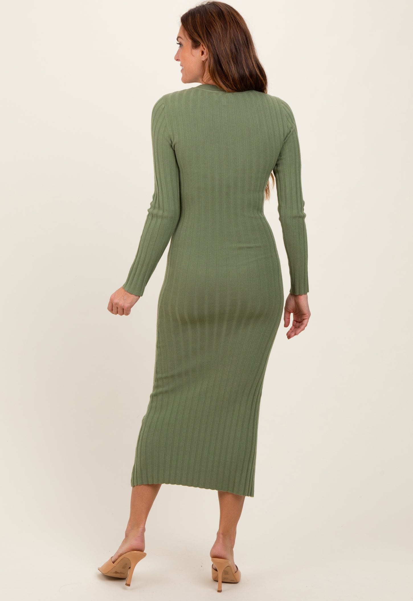 woman wearing a green ribbed long sleeve midi dress, viewed from the back, with a fitted silhouette and a split hem
