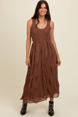 woman wearing a brown maxi dress with a smocked bodice and pleated skirt, paired with black cowboy boots