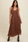 woman wearing a brown maxi dress with a smocked bodice and pleated skirt, paired with black cowboy boots