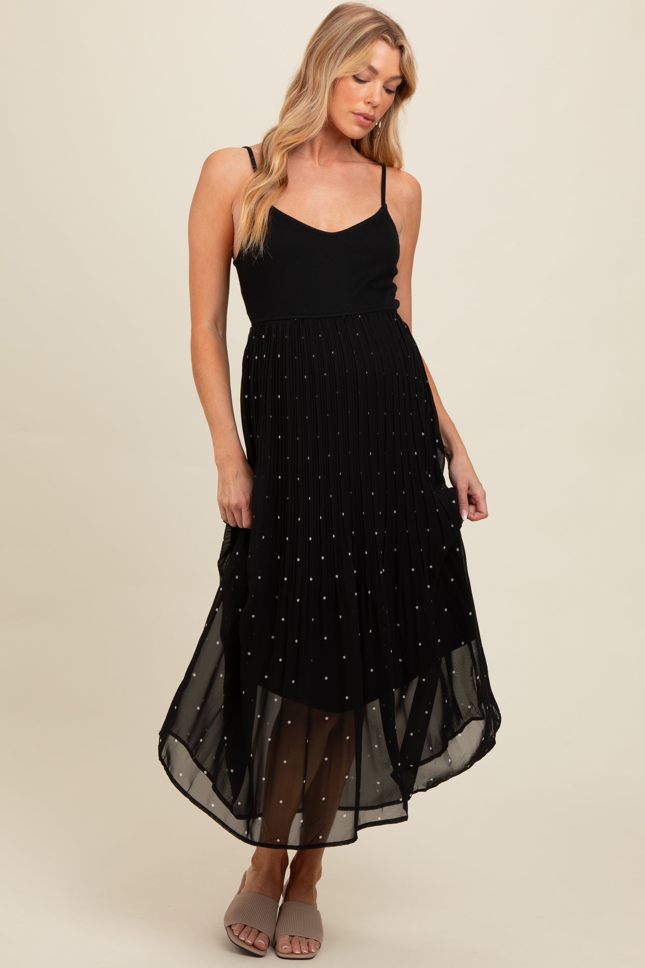 woman wearing a black maternity dress with spaghetti straps and a pleated skirt adorned with small sequins