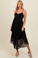 woman wearing a black maternity dress with a flowy skirt and subtle dot details, showcasing her baby bump