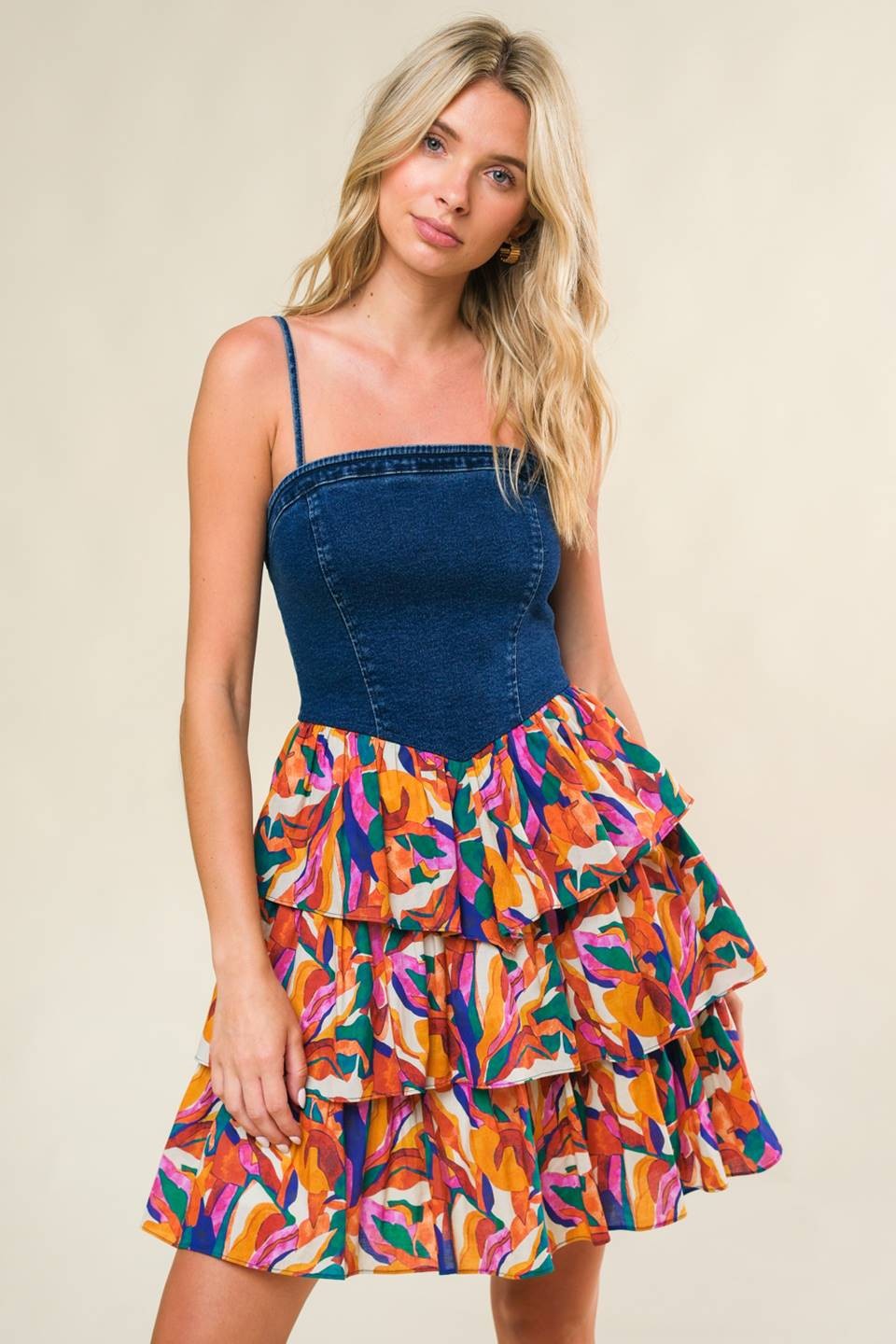 woman wearing a denim bodice dress with a colorful ruffled floral skirt