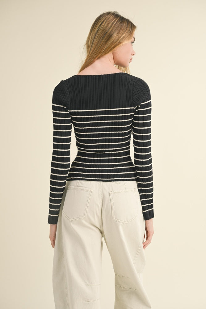 woman wearing a black and white striped ribbed long sleeve top and beige wide-leg pants, showing the back view